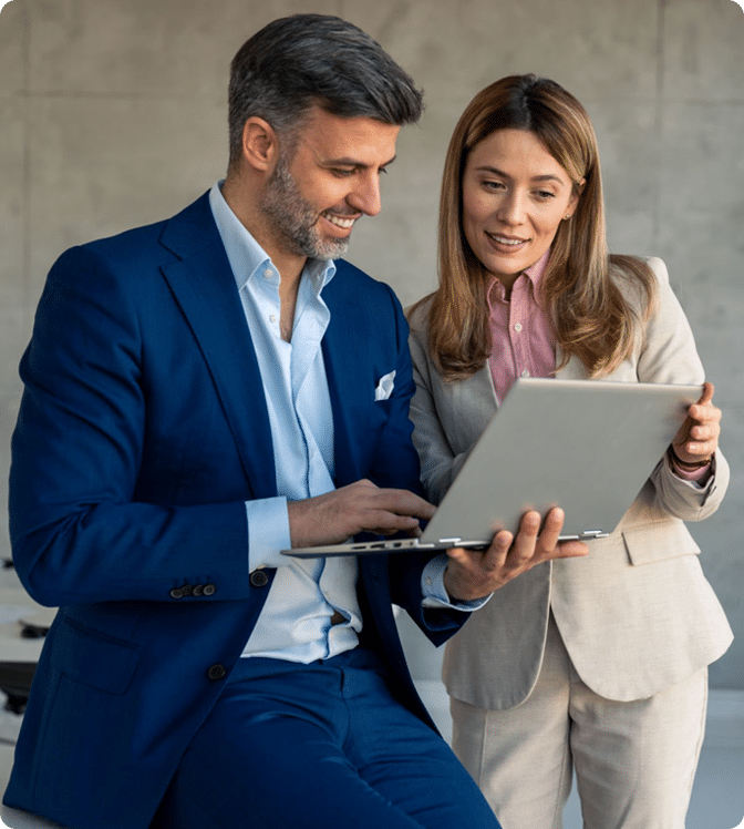 Two professionals standing together, looking at a laptop in an office setting. This keeps it short, clear, and accessible while capturing the key elements. Would you like me to also create a slightly longer version that emphasizes collaboration and teamwork for SEO or business contexts?